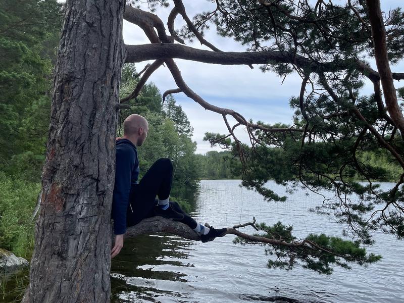 Me sitting on a tree branch by a lake in Norway